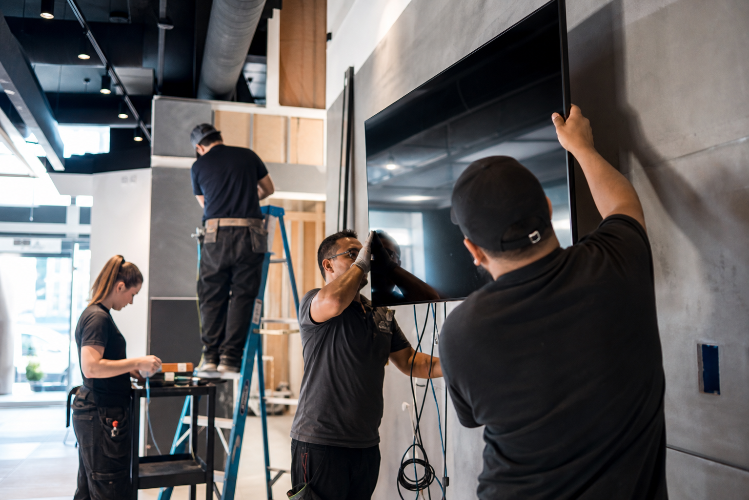 Installers Mounting Digital Screen in Retail Space