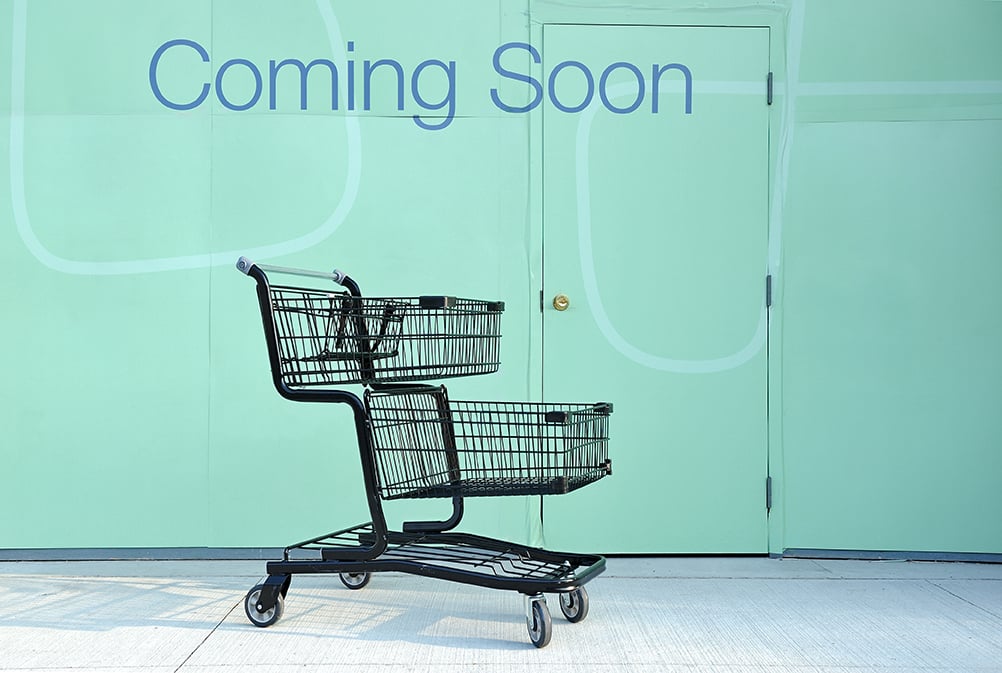 "Coming soon" sign on a wall and shopping cart