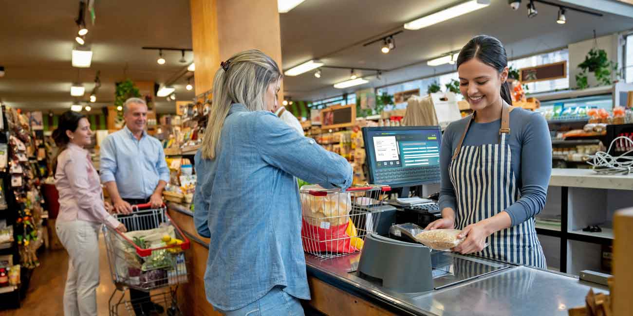 Blonde woman grocery shopping customer checking out at the register with cashier