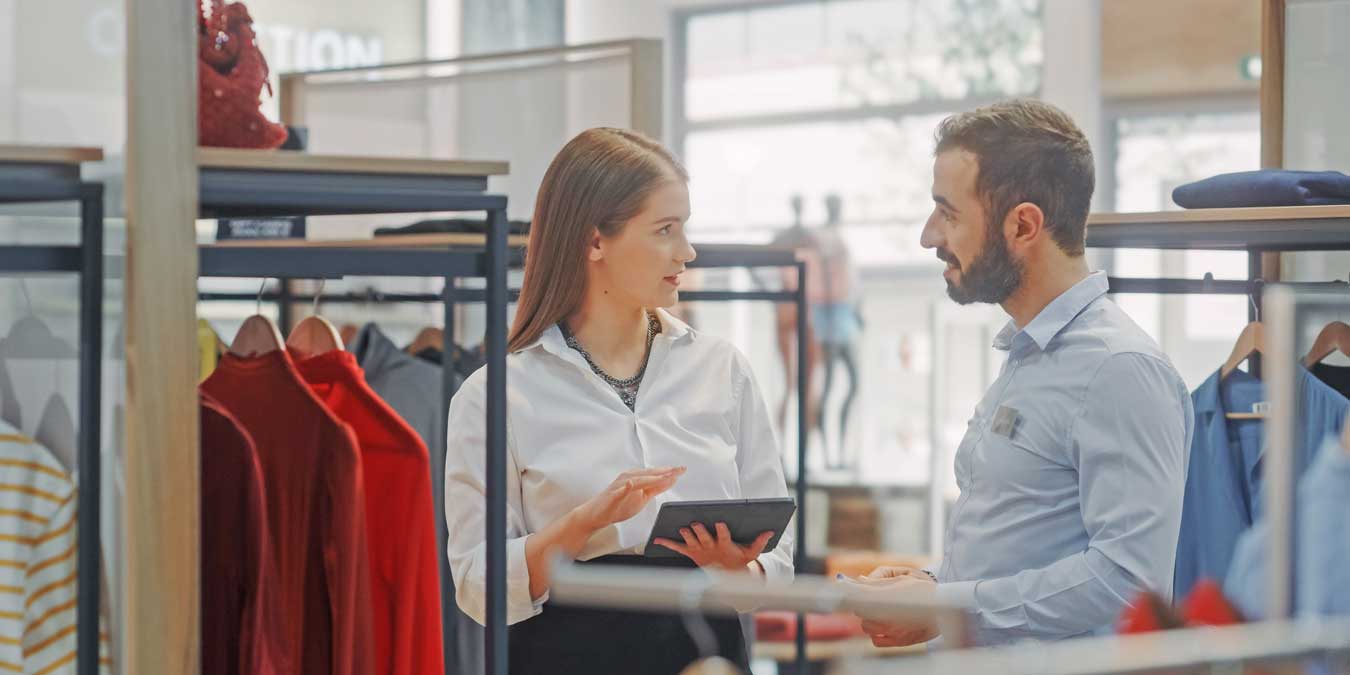 Woman associate in clothing store assisting customer gentleman